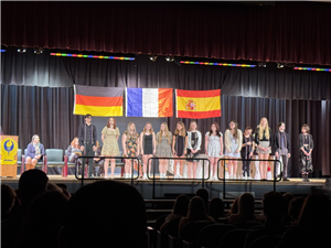 Students in World Languages stand on stage with honors cords around neck
